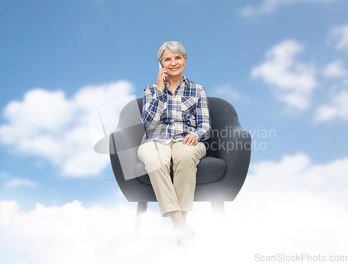Image of senior woman calling on smartphone in armchair