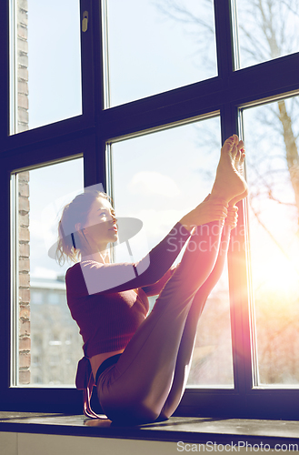 Image of woman doing yoga exercise on window sill at studio