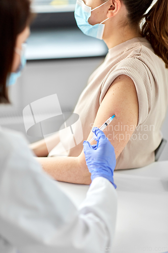 Image of female doctor with syringe vaccinating patient