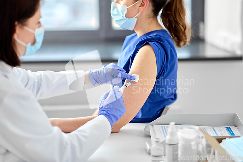 Image of doctor with syringe vaccinating medical worker