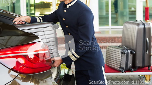 Image of Bellboy taking baggage of guest from thee car to his room