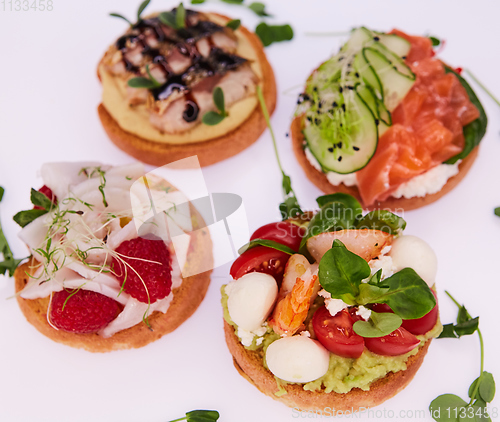 Image of four different bruschettes with salmon, mackerel, shrimp and halibut.