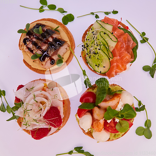 Image of four different bruschettes with salmon, mackerel, shrimp and halibut.