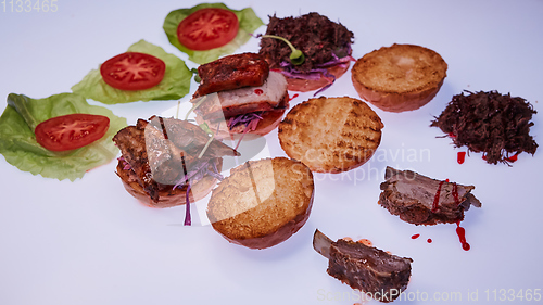 Image of Three open burgers with different fillings with a torn pork, with ribs and pork ribs on a white table