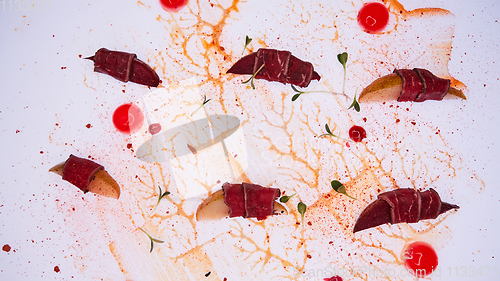 Image of Prosciutto with pear on white table. Traditional Mediterranean snack