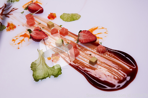 Image of Conceptual Salad of Salmon and Avocado Cubes. Decorated with sauce, strawberries and green leaves