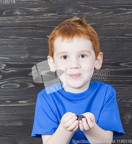 Image of red-haired boy holds blueberry