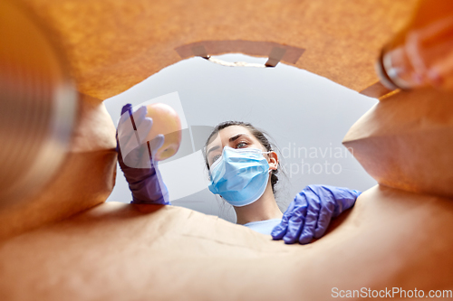 Image of woman in gloves and mask with food in paper bag