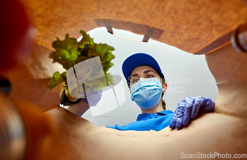 Image of delivery girl in gloves and mask with food in bag