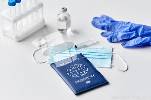 Image of immunity passport, mask, syringe, vaccine on table