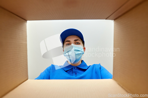Image of woman in mask looking inside cardboard parcel box