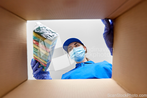 Image of woman in mask packing kitchen sponges to box