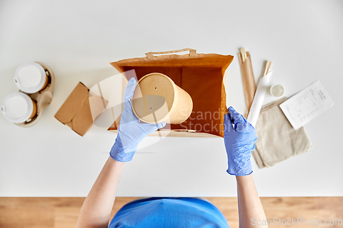 Image of delivery woman in gloves packing food and drinks