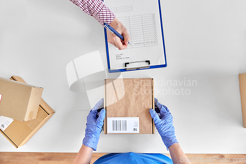 Image of hands with parcel box and customer signing papers