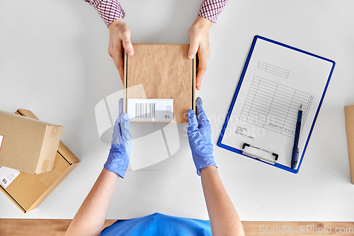 Image of hands in gloves giving parcel box to customer