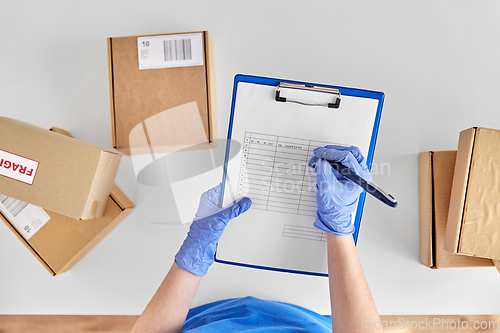 Image of hands in gloves with clipboard and parcel boxes