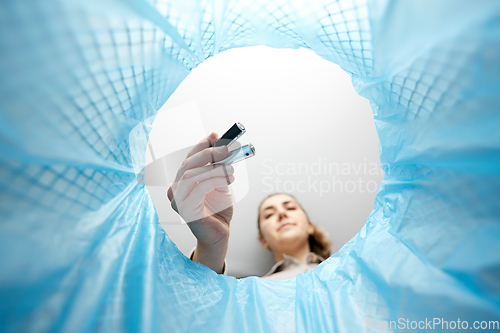 Image of woman throwing alkaline batteries into trash can