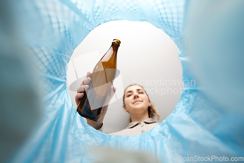 Image of woman throwing glass bottle into trash can