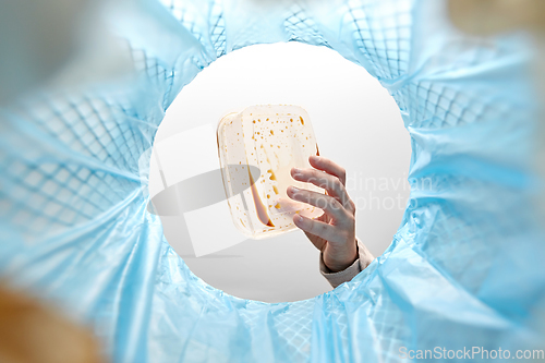 Image of hand throwing plastic container into trash can