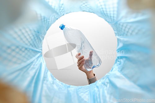 Image of hand throwing plastic bottle into trash can