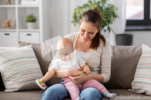 Image of mother and little baby playing with rattle at home