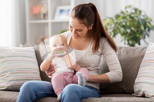 Image of mother and little baby with teething toy at home