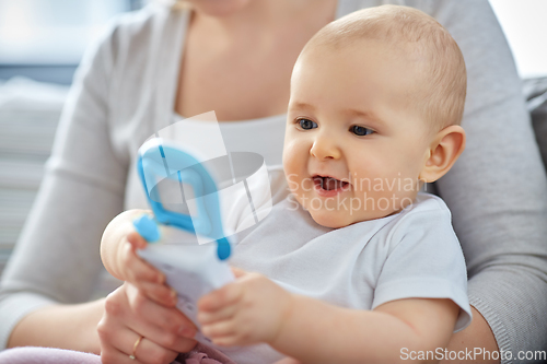 Image of mother with baby playing with toy phone at home