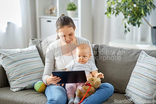 Image of happy mother and baby girl with tablet pc at home