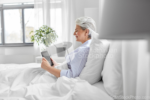 Image of senior woman with tablet pc in bed at home bedroom