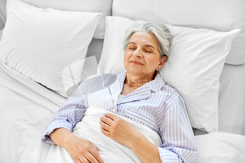 Image of happy senior woman sleeping in bed at home bedroom