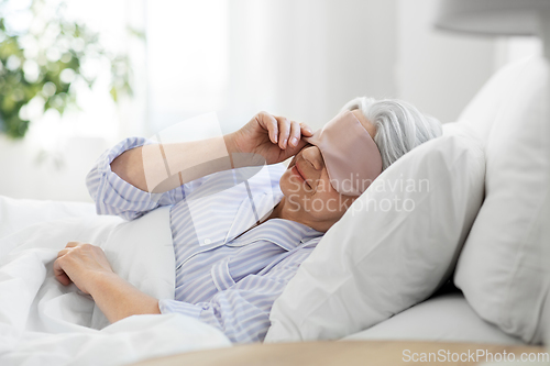 Image of senior woman with eye sleeping mask in bed at home