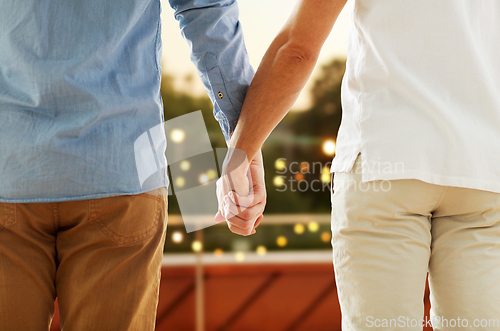 Image of close up of happy male gay couple holding hands