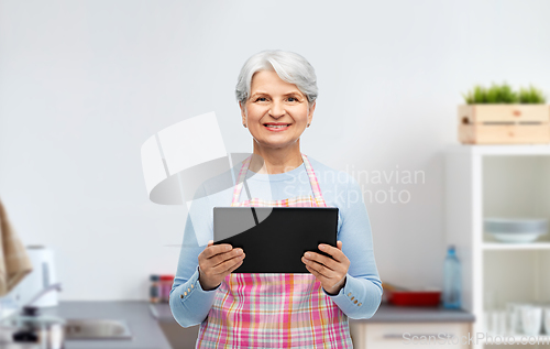 Image of smiling senior woman with tablet pc at kitchen