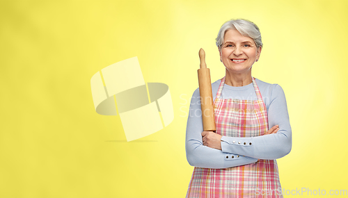 Image of smiling senior woman in apron with rolling pin
