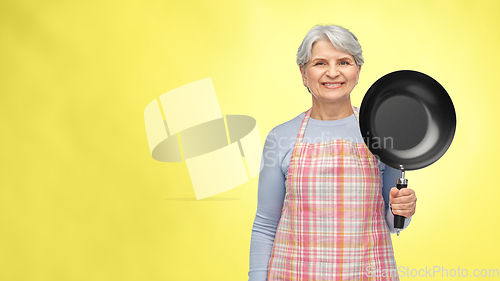 Image of smiling senior woman in apron with frying pan