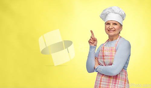 Image of smiling senior woman or chef pointing finger up