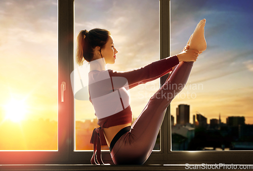 Image of woman doing yoga exercise on window sill at studio