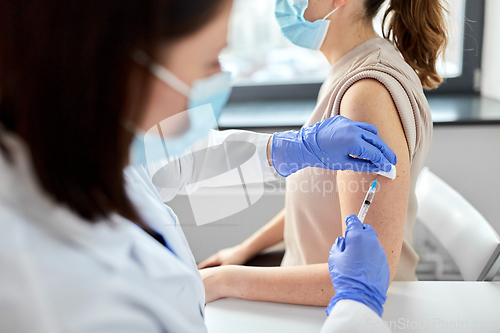 Image of female doctor with syringe vaccinating patient