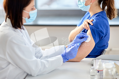 Image of doctor with syringe vaccinating medical worker