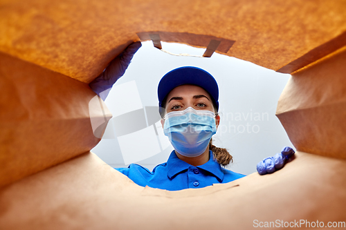 Image of delivery girl in gloves and mask with food in bag