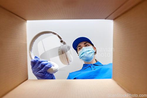 Image of woman in mask packing headphones into parcel box