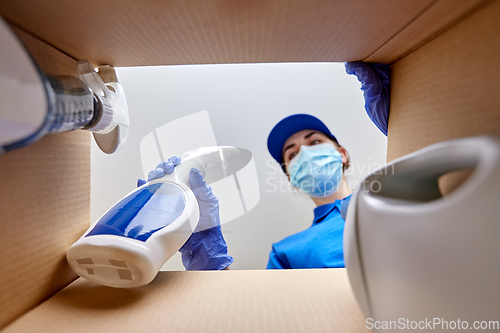 Image of woman in mask packing cleaning supplies in box