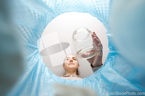 Image of woman throwing glass jar into trash can