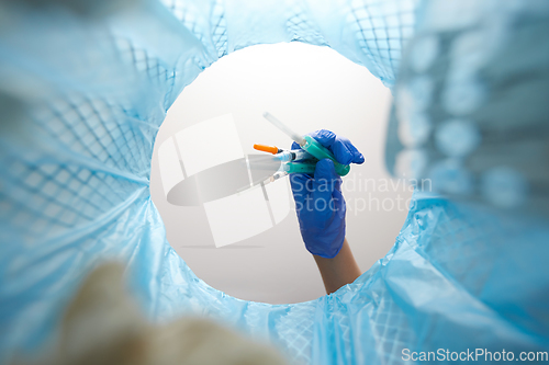 Image of hand throwing used syringes into trash can