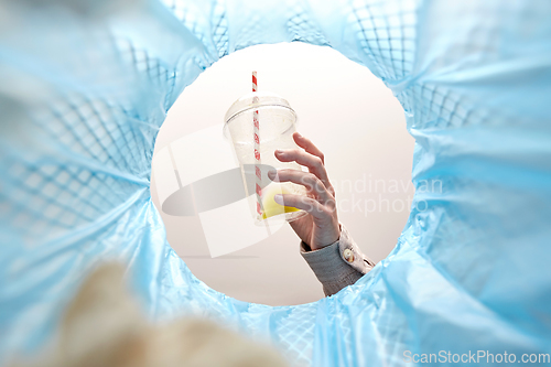 Image of hand throwing plastic cup into trash can