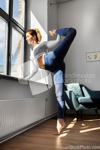 Image of woman doing yoga exercise at window sill at studio