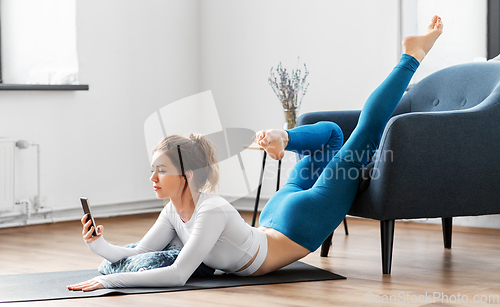 Image of woman with smartphone stretching yoga at home