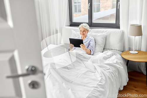 Image of senior woman with tablet pc in bed at home bedroom