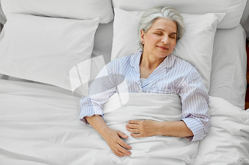 Image of happy senior woman sleeping in bed at home bedroom