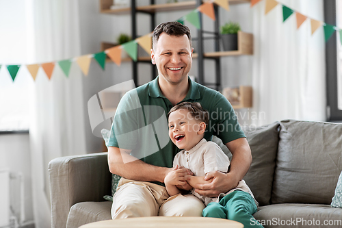 Image of happy father and little son at home birthday party